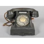 A vintage bakelite black telephone, with chrome dial and pull out number tray,