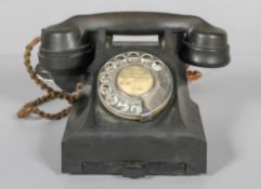 A vintage bakelite black telephone, with chrome dial and pull out number tray,