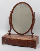 An early 19th century inlaid mahogany oval swing dressing table mirror,