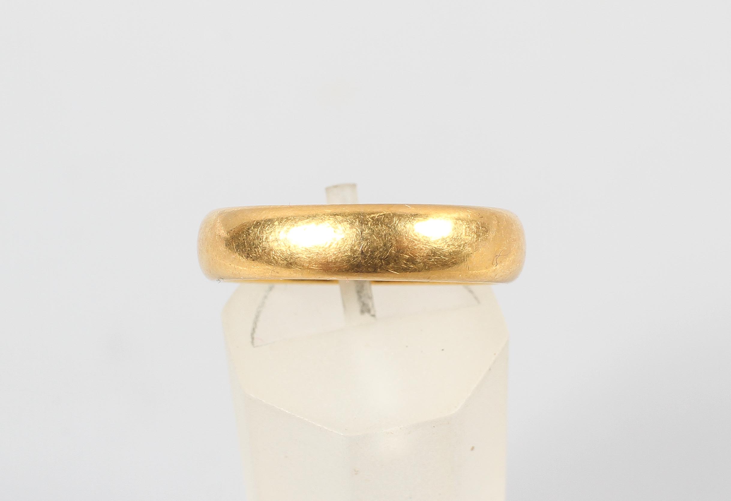 A yellow metal 4.5mm court shaped wedding ring. Hallmarked 22ct gold, Birmingham, 1925. Size: M 7.