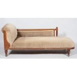 A Victorian oak chaise longue, the oak frame carved with foliate scrolls,