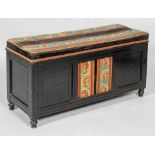 A Victorian ebonised ottoman-chest, of low rectangular section, with square recessed panelled front,