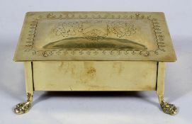 An Arts and Crafts brass box, the domed lid with engraved crest, on paw feet,