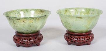 A pair of Chinese carved translucent green spinach jade bowls and hardwood stands, 20th century,