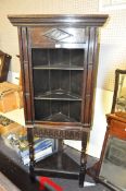 An oak corner cupboard of Tudor form with three shelf open unit on a turned leg base with an