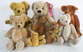 A Merrythought blond plush teddy bear with seven other bears