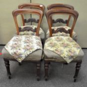 A set of four balloon back chairs in mahogany with carved back rails, raised on turned legs