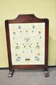 A needlework fire screen in dark stained oak frame