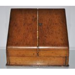 A small Victorian oak stationery cabinet with two slope front doors to a fitted interior