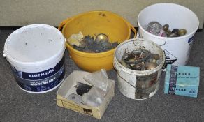 A collection of metal door knobs, handles and an unopened tub of mortar.