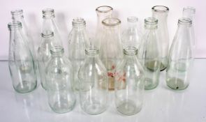 A collection of sixteen glass milk bottles. Tallest measures; 23cm.