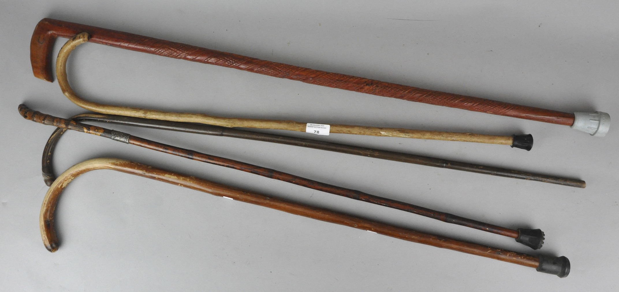 A collection of five wooden walking sticks and canes to include a silver mounted example.