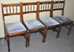 A set of four stained pine dining chairs.