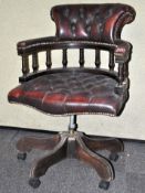 An ox blood red leather Chesterfield captain chair raised on a five point base and castor.