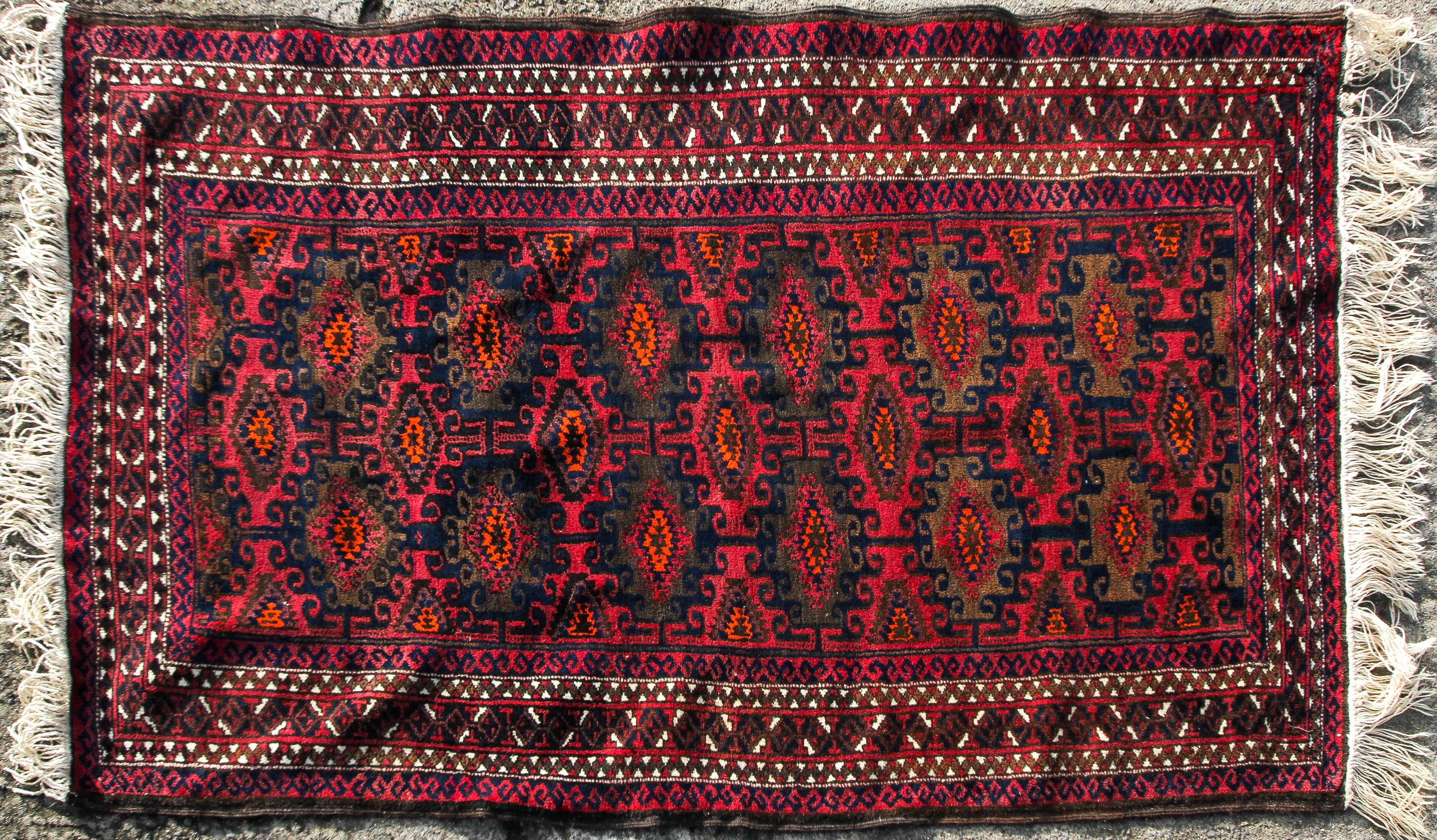 An Afghan carpet, decorated in tones of orange and brown on a predominantly maroon ground,