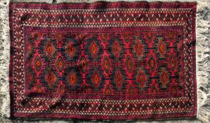 An Afghan carpet, decorated in tones of orange and brown on a predominantly maroon ground,