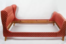 A French sleigh bed, upholstered with a red fabric decorated with anthemions,
