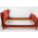 A French sleigh bed, upholstered with a red fabric decorated with anthemions,