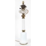 A gilt metal and milk glass oil lamp with a clear glass reservoir on a mallet form body,
