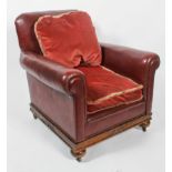 An early 20th century red leather Club armchair, with red velvet drop in cushions, with scroll arms,