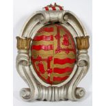 A 19th century carved wood and gesso crest, the scrolled body with central domed coat of arms,