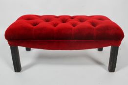 A George III style ebonised foot stool, the button back top upholstered in cherry red velvet,