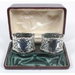 A pair of boxed silver napkin rings, of pierced geometric foliate form with cast shaped borders,