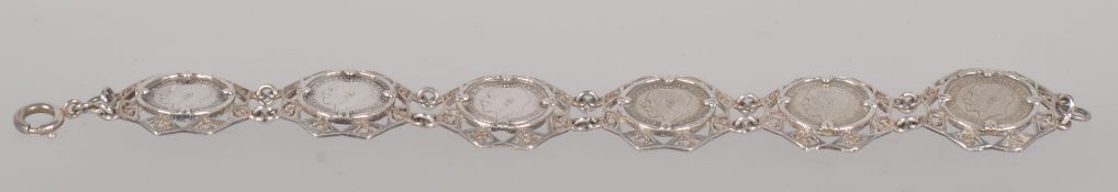 A white metal abstract linked bracelet, each set with a threepenny bit dating from 1917 to 1921.