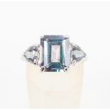 A white metal three stone ring set with rectangular and trilliant cut coated topaz.
