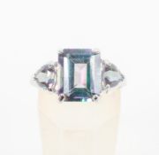 A white metal three stone ring set with rectangular and trilliant cut coated topaz.