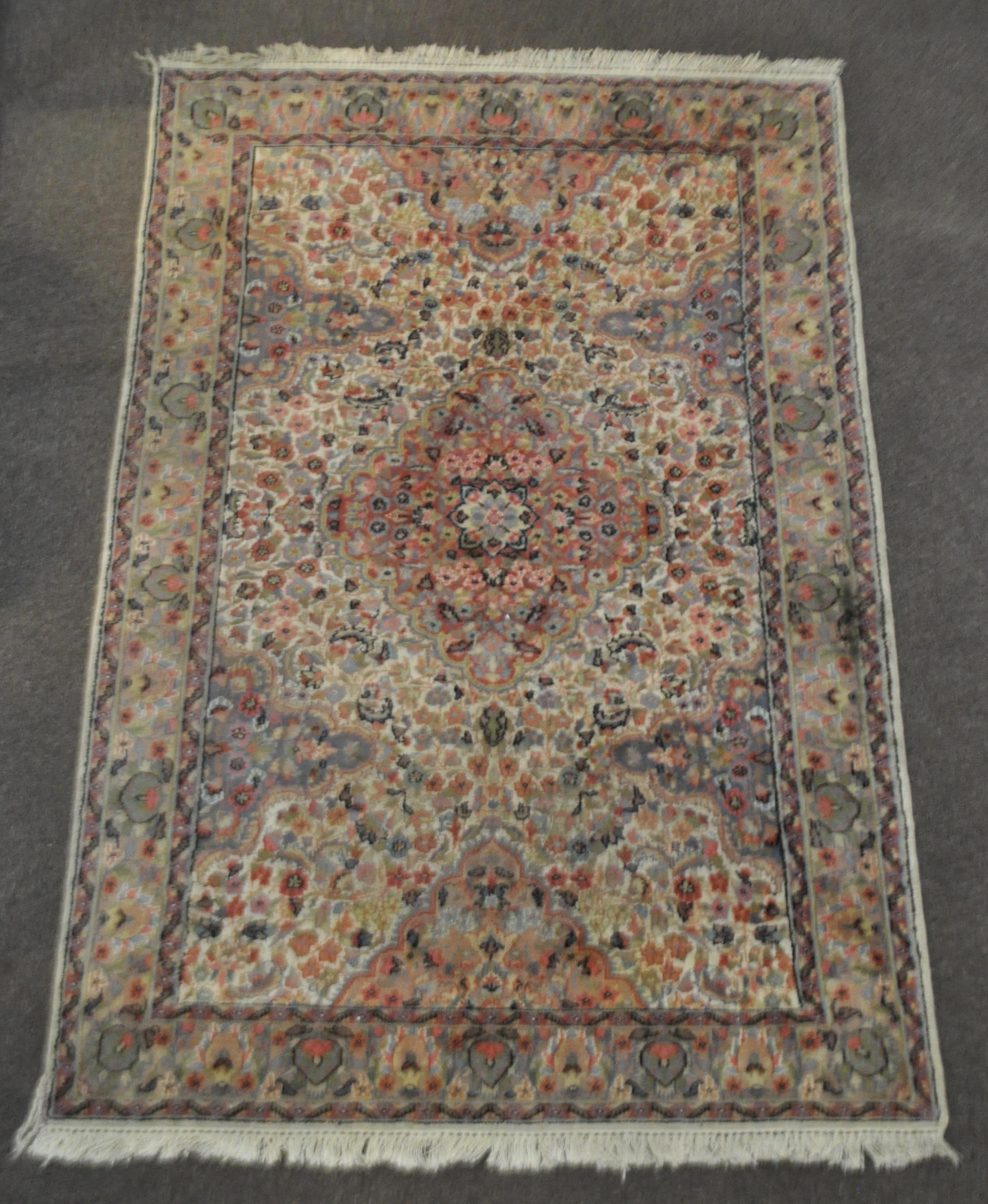 A Middle Eastern carpet the central cream ground with central medallion and floral decoration