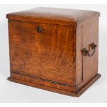 An Edwardian oak stationery cabinet, the hinged cover and fall front enclosing a fitted interior,
