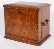 An Edwardian oak stationery cabinet, the hinged cover and fall front enclosing a fitted interior,