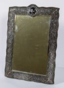 A late Victorian silver mirror, the pierced foliate frame on velvet back,