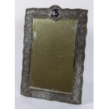 A late Victorian silver mirror, the pierced foliate frame on velvet back,