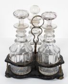 A late Victorian ebonised three decanter frame with a set of three glass spirit decanters