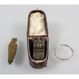 A collection of items: A Platinum wedding ring, a gold plated sarcophagus; a silver scarf buckle