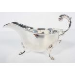 A silver sauce boat, with acanthus open scroll handle over a bead edge, raised on cabriole pad feet,