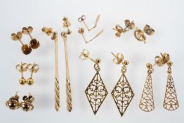 A collection of eight pairs of yellow metal drop earrings of variable designs. Gross weight: 9.