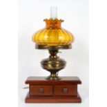 A wooden mounted electrified oil lamp with amber shade and chimney