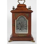 An oak cased mantel time piece, the metal dial with chapter ring on a brass movement,