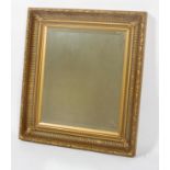 A bevelled mirror plate in a heavy gilt concave fluted frame with laurel leaf border,
