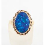 A yellow metal ring set with an oval cabochon cut synthetic black opal. Hallmarked 9ct gold, London.