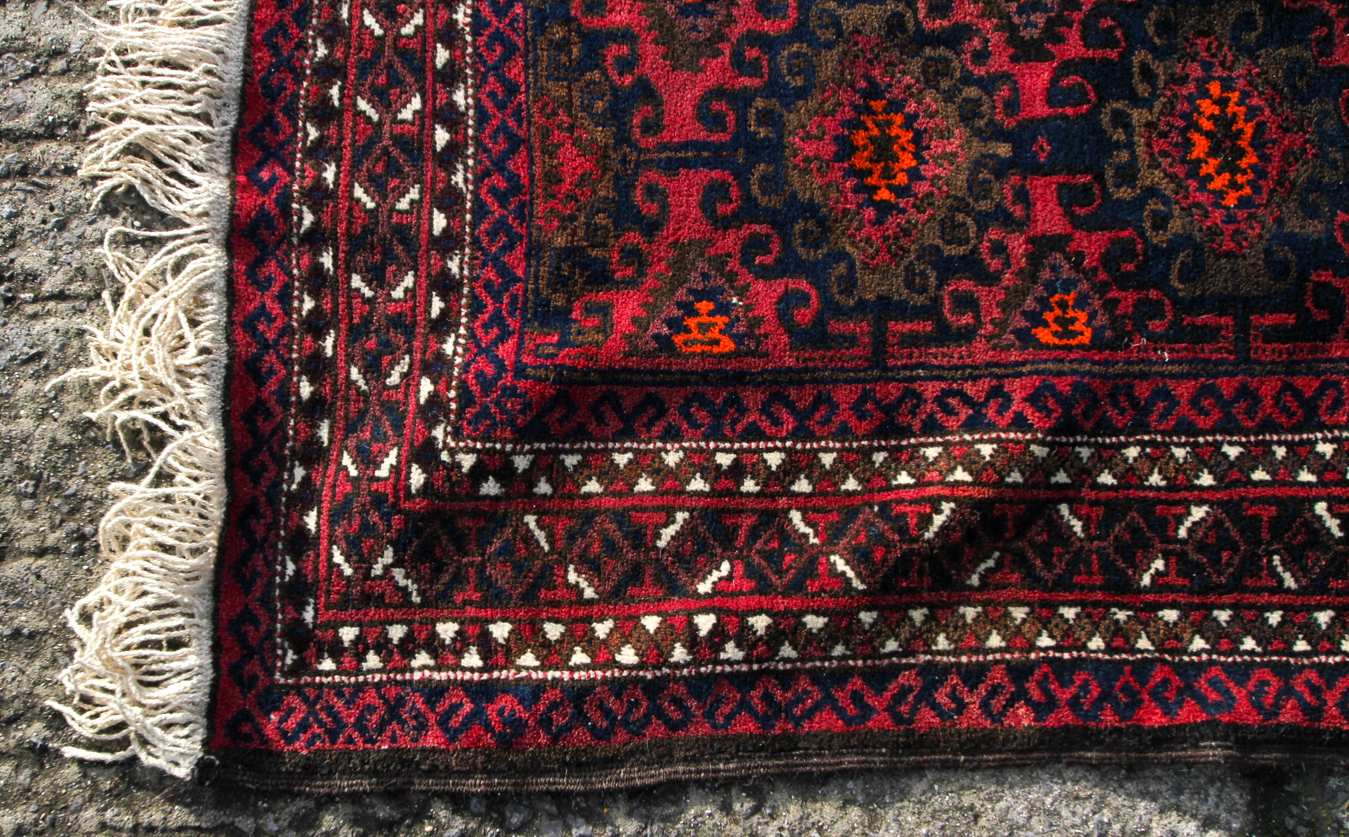 An Afghan carpet, decorated in tones of orange and brown on a predominantly maroon ground, - Image 2 of 3