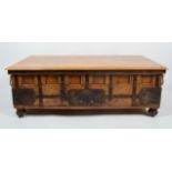 An Indian hardwood iron bound coffee table with plain bevelled edge top over a panelled body with