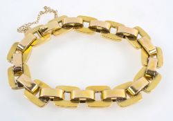 A yellow metal hollow linked bracelet with push in clasp and fitted safety chain.