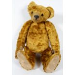 An antique teddy bear with hump back and long snout, jointed, with glass eyes,