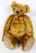 An antique teddy bear with hump back and long snout, jointed, with glass eyes,
