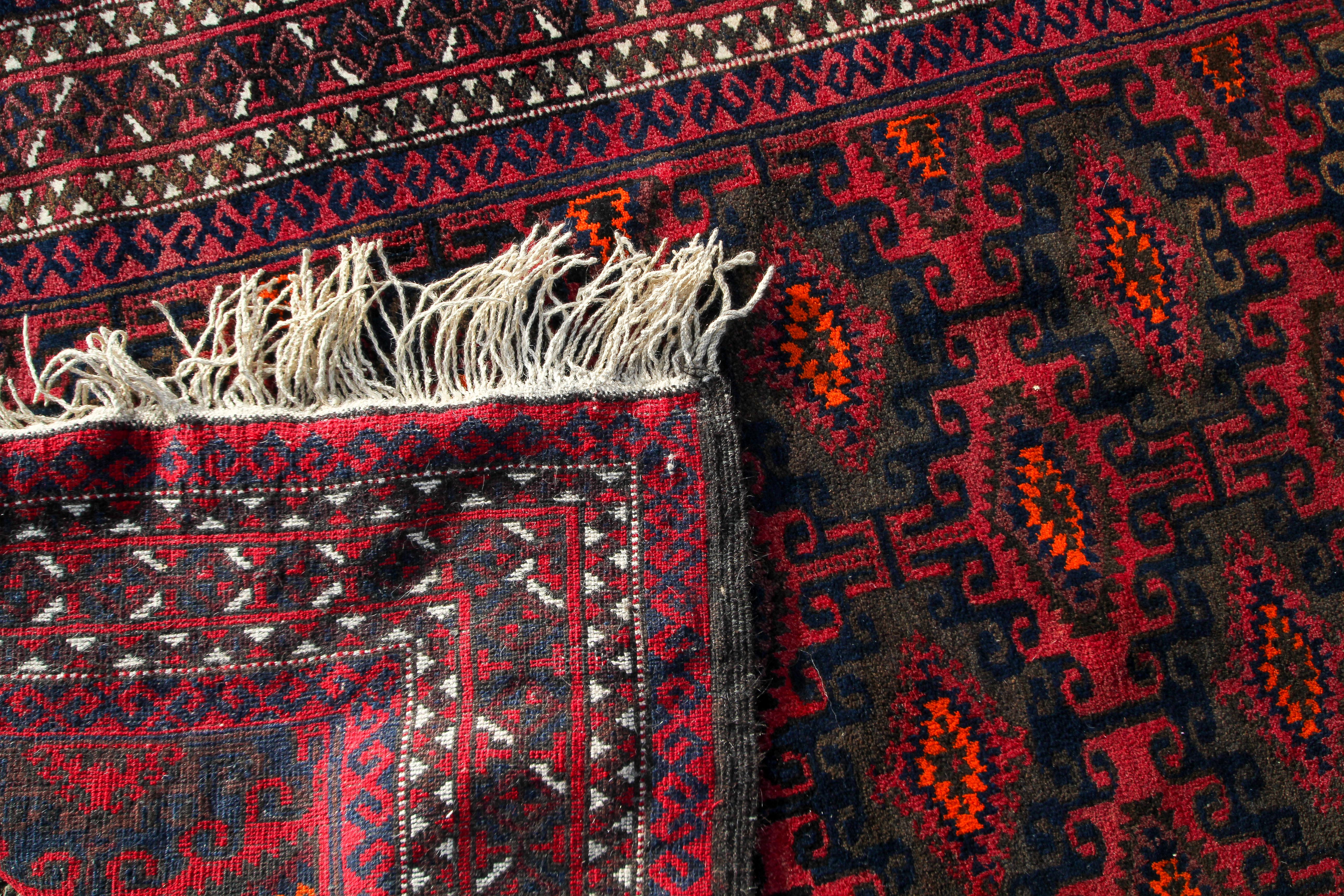 An Afghan carpet, decorated in tones of orange and brown on a predominantly maroon ground, - Image 3 of 3