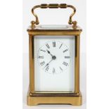 A brass carriage time piece, the white enamelled dial with black Roman numerals,